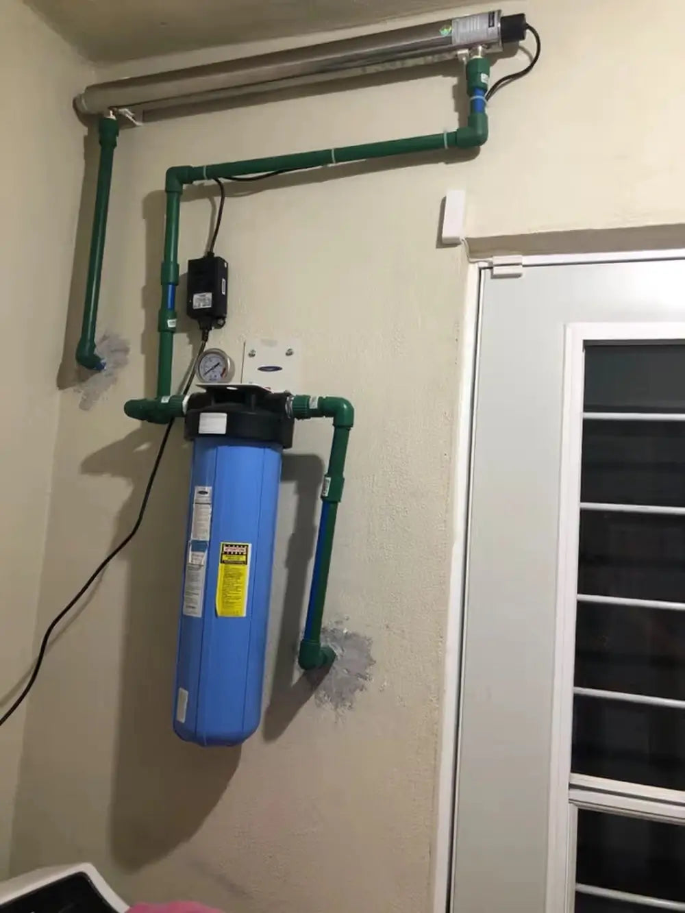 Crystal Quest Big Blue SMART single whole house water filter installed with UV water sterilizer and green piping.