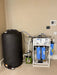 Complete Crystal Quest whole house RO installation including the filtration rack, a large black water storage tank, and a green delivery pump.
