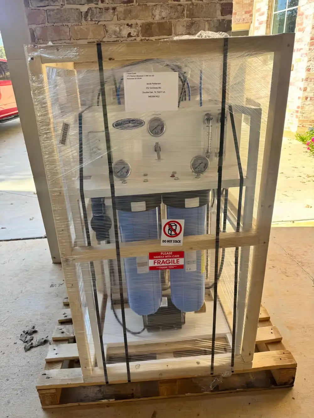 A Crystal Quest whole house reverse osmosis system securely packaged in a wooden shipping crate and palletized for safe delivery.