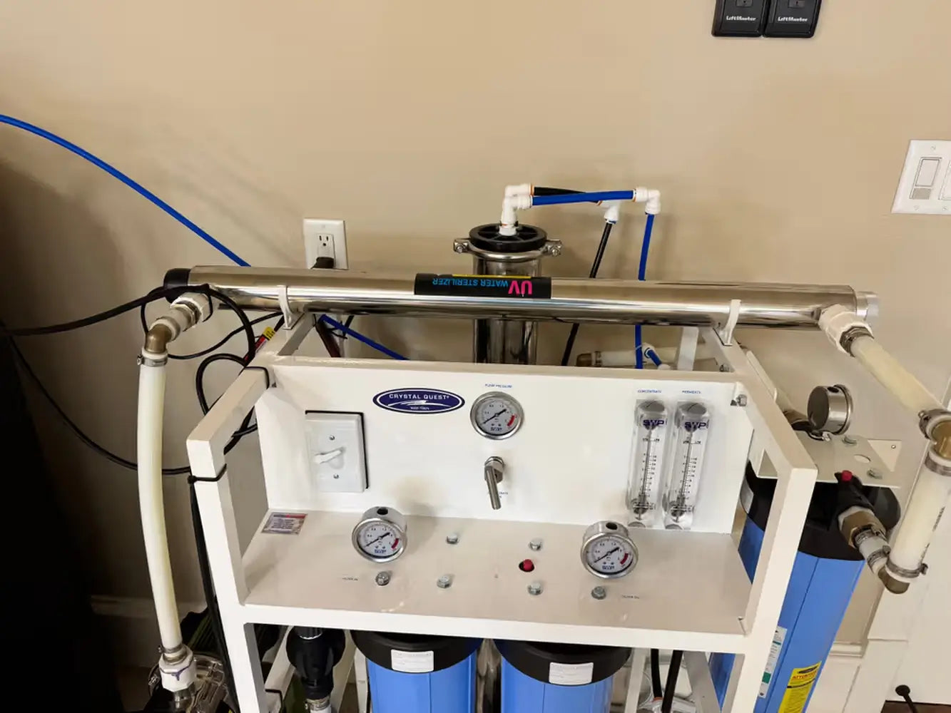 Close-up of a Crystal Quest RO system control manifold showing flow meters, pressure gauges, and an integrated UV water sterilizer.