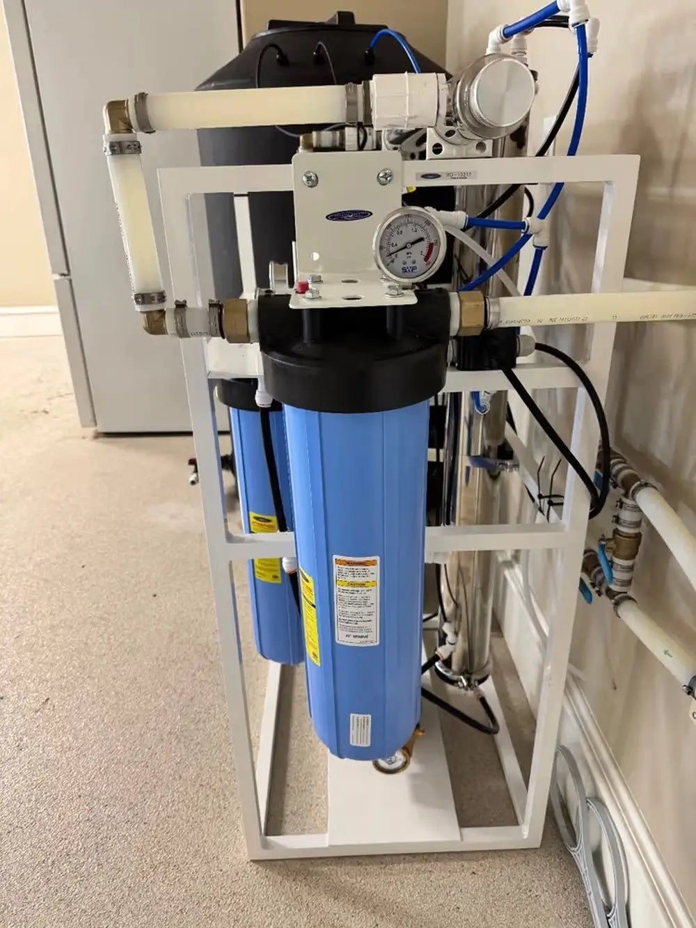 Dual Crystal Quest Big Blue SMART whole house water filtration system on a white floor stand with pressure gauge.
