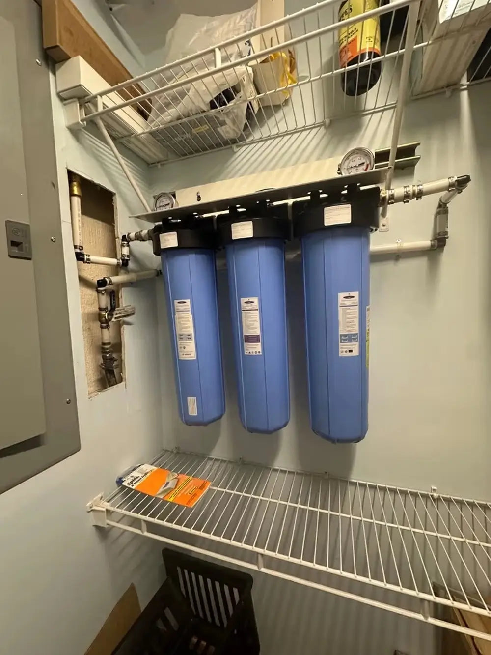 Triple Crystal Quest Big Blue SMART whole house water filter wall-mounted in a utility closet with pressure gauges.