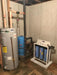 Crystal Quest Big Blue SMART triple whole house water filter system on floor stand installed in a basement near a water heater.