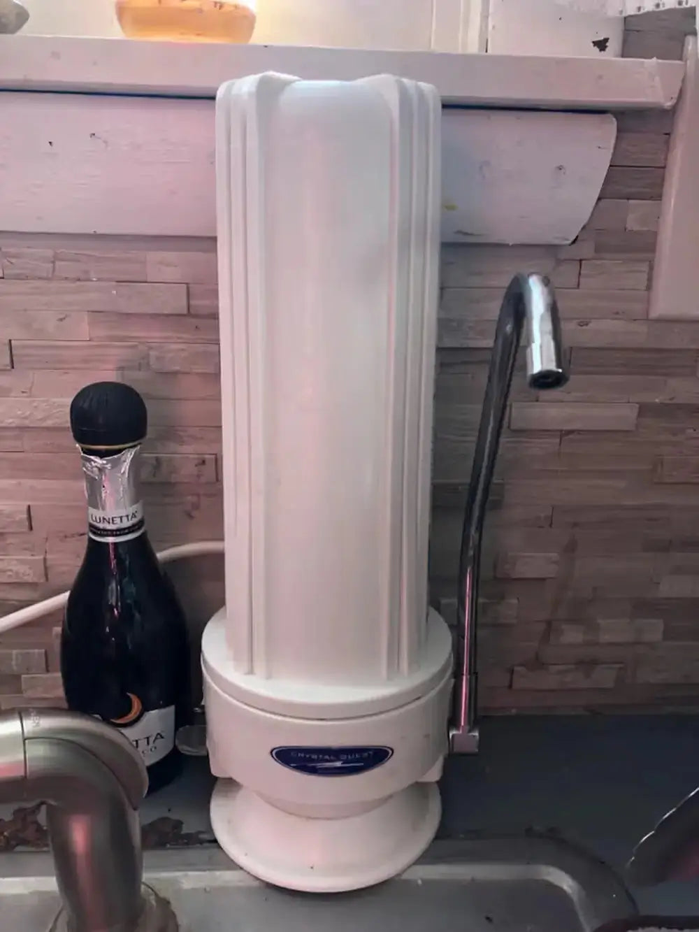 Crystal Quest Fluoride SMART white countertop water filter system installed on a kitchen sink in a home setting.