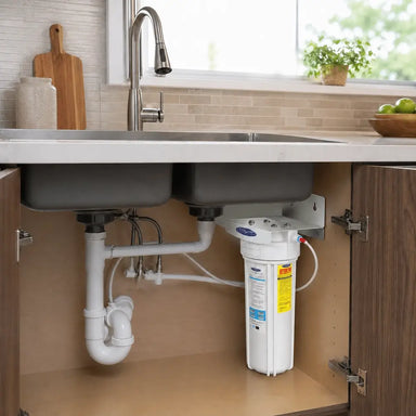 Space-saving under-sink water filter for fluoride removal by Crystal Quest shown with plumbing connections.