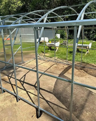 Interior view of the heavy-duty galvanized steel frame of a Magnolia 10x13 Greenhouse Kit during the assembly process.