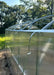 Detailed view of polycarbonate panel installation with metal securing straps on the side of a GreenhouseToGrow Magnolia greenhouse.