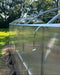Side view of the Magnolia 10x39 Greenhouse showing the installation of polycarbonate panels secured with metal wind straps for added stability.