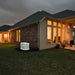 Generac 10kW aluminum standby generator powering modern home exterior at dusk