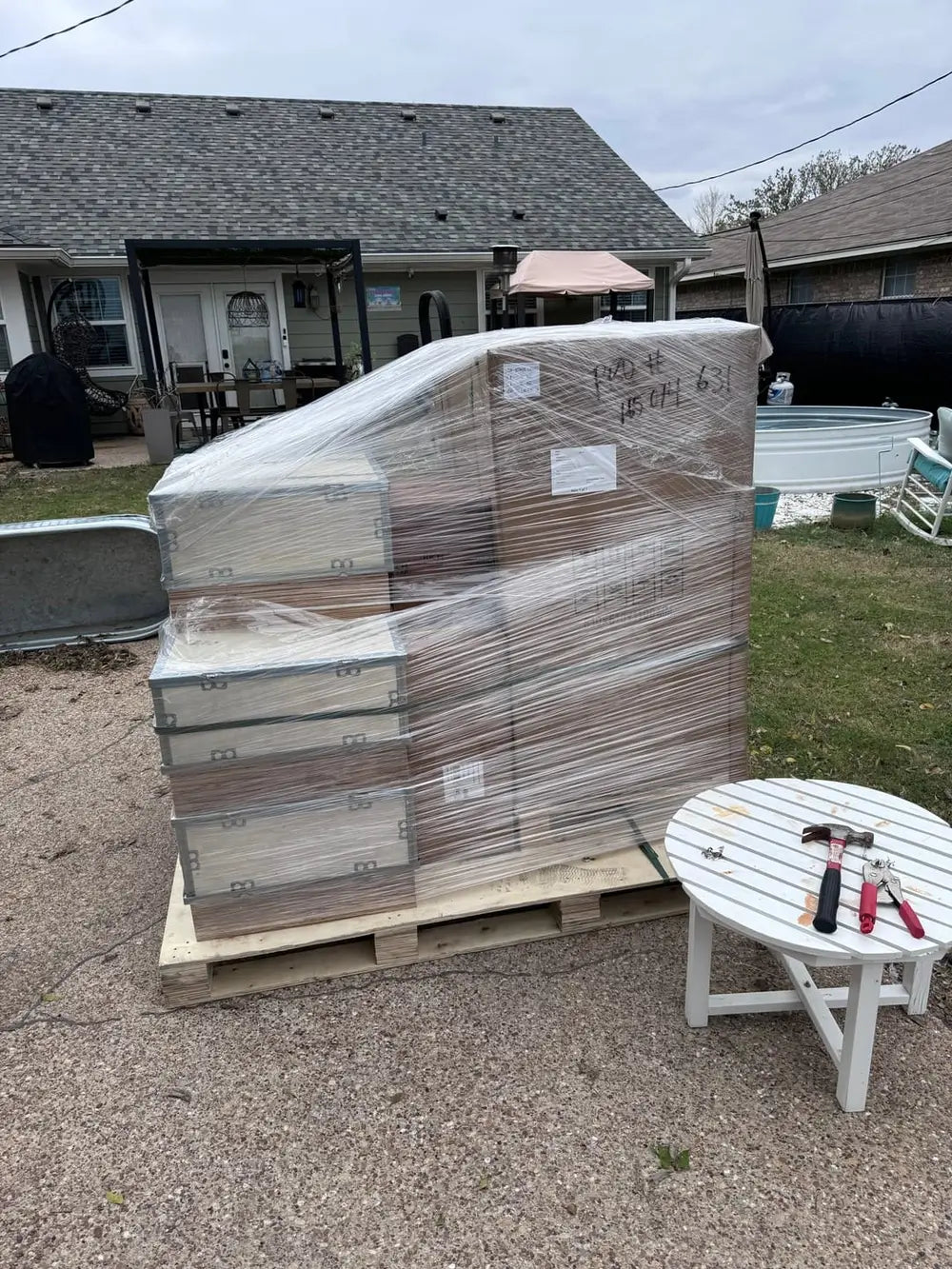 Cardboard boxes of a Rich Solar battery system safely stacked and shrink-wrapped on a wooden delivery pallet in a residential driveway.