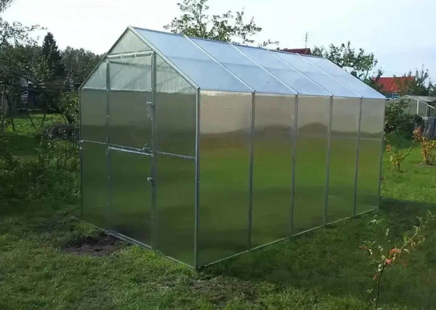 Fully assembled GreenhouseToGrow Daisy 8.3'x32.5' Greenhouse Kit with clear polycarbonate panels and closed Dutch door.