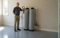 Professional technician standing next to an indoor installation of the AlkaViva UltraHome Single Filtration and Softener dual-tank system in a home garage.