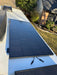 Close-up of an all-black Rich Solar 250W monocrystalline solar panel mounted flat on a white RV roof with disconnected MC4 cables.
