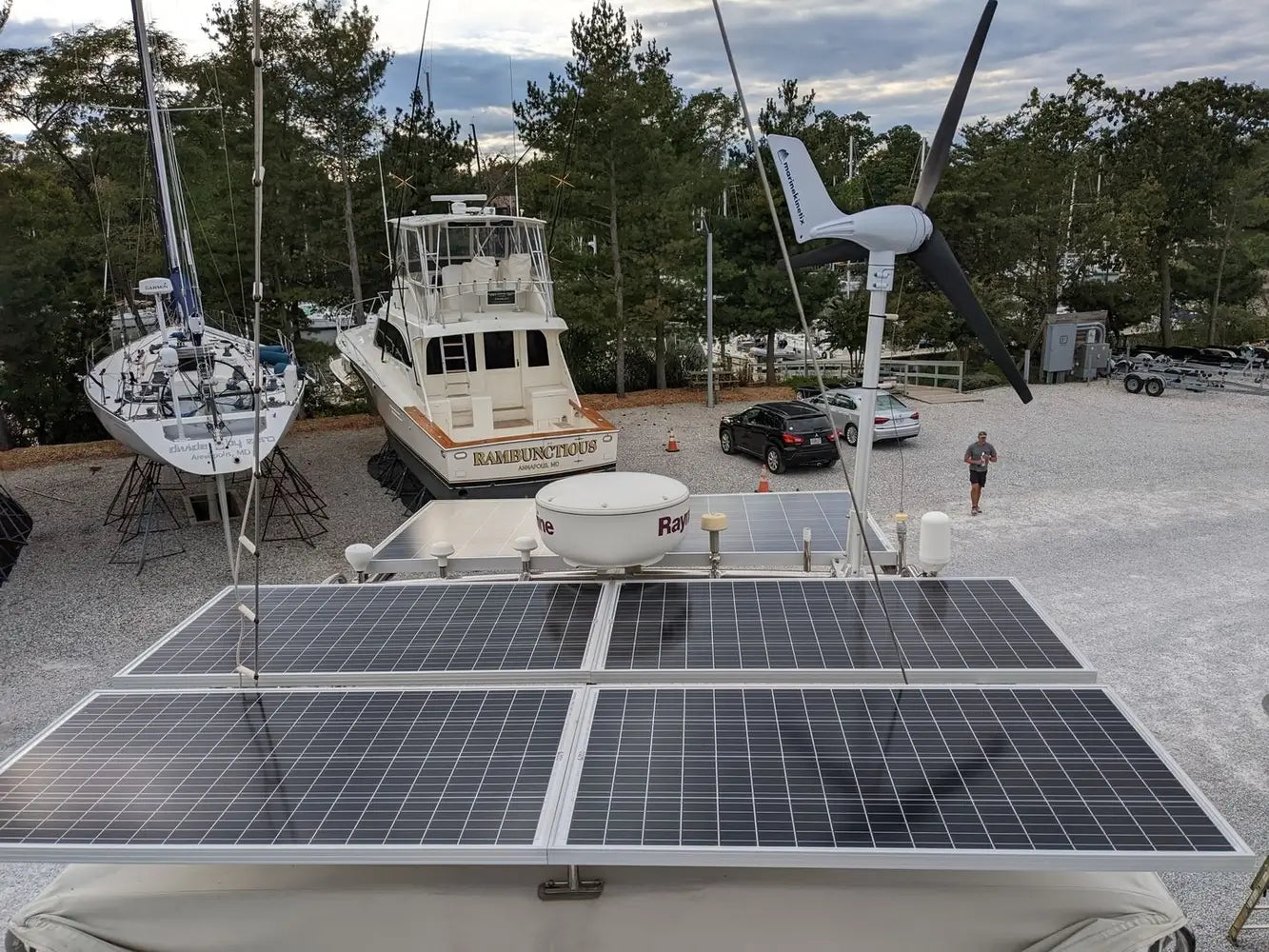 Marine solar panel array and a marine wind turbine mounted on a yacht hardtop in a boatyard for off-grid hybrid power.