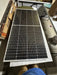 Rich Solar MEGA 250 PRO 24V monocrystalline solar panel with silver frame lying flat on a workbench next to its original cardboard packaging.