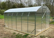 The completed GreenhouseToGrow Magnolia 10x13 Greenhouse Kit installed on a level wood and gravel foundation in a garden setting.