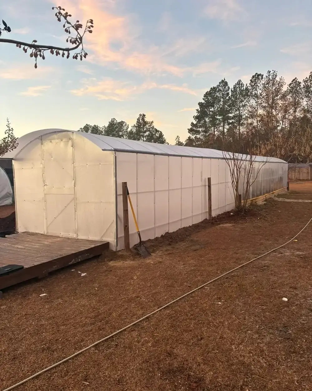 Wide-angle exterior view of the GreenhouseToGrow Magnolia 10x39 Greenhouse Kit during the final stages of garden installation.