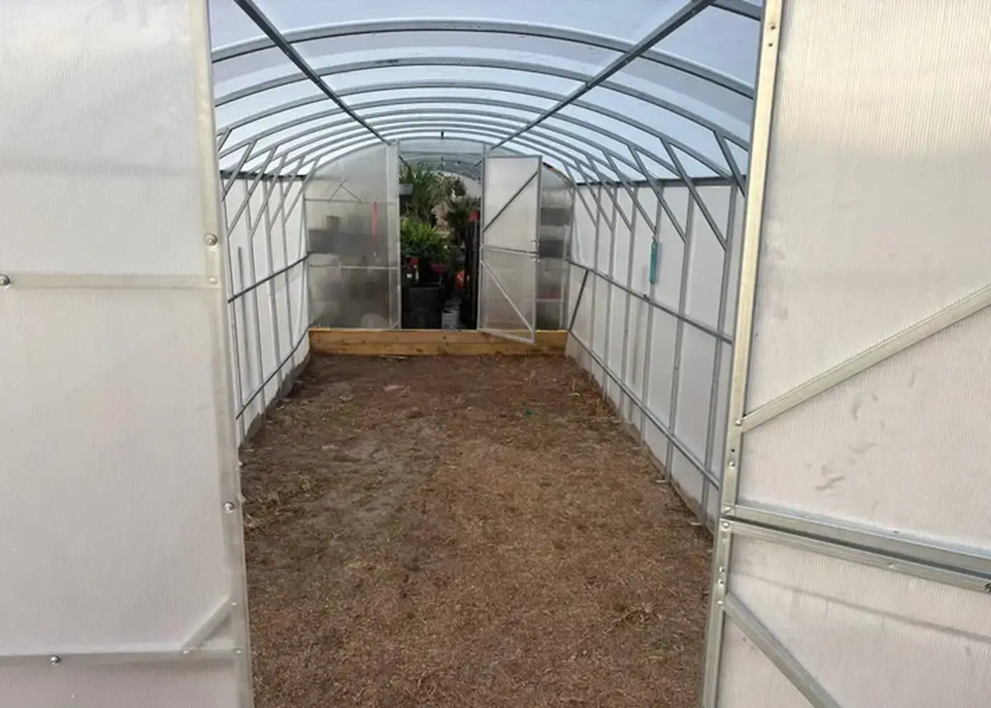 Interior walkway view of the GreenhouseToGrow Magnolia 10x39 Greenhouse Kit showing the spacious 39-foot length and vaulted ceiling structure.
