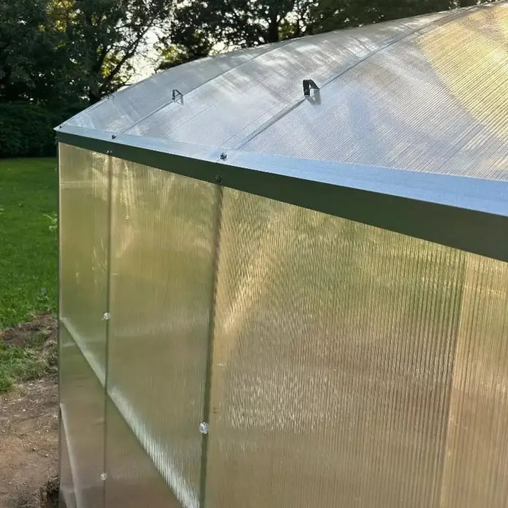 Corner detail of the Magnolia 10x6.5 Greenhouse Kit showing the aluminum trim and secure fastening of the translucent wall panels.