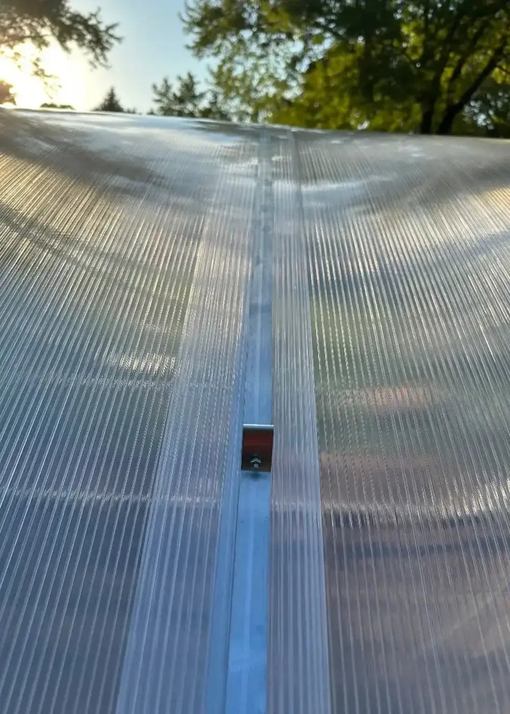 Extreme close-up of the polycarbonate roof seam and weather-tight mounting hardware on a GreenhouseToGrow Magnolia greenhouse.