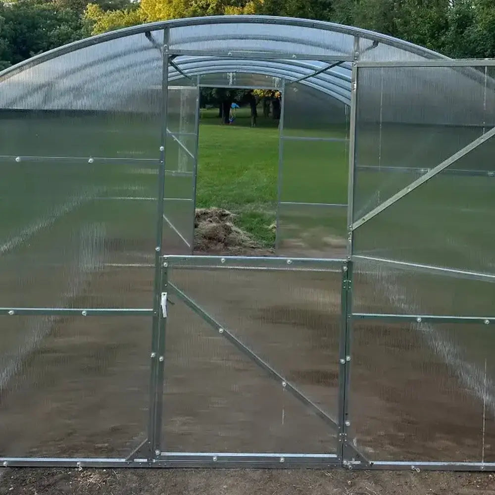 Front view of the Magnolia 10x6.5 Greenhouse Kit entrance showcasing the clear polycarbonate walls and internal structural supports.