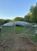 Front entrance view of a GreenhouseToGrow Magnolia 10x32.5 Greenhouse Kit with Dutch doors overlooking a grassy field.