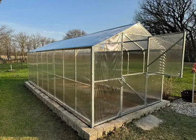 Side-angle view of the Daisy 19.5-foot long greenhouse kit with the top half of the Dutch door open for ventilation and airflow.