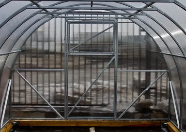 Close-up of the front end wall and door frame of a GreenhouseToGrow Camellia 10x32.5 Greenhouse Kit showing the heavy-duty galvanized steel structure and polycarbonate panels.