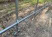 Close-up detail of the GreenhouseToGrow Camellia 10x6.5 Greenhouse Kit’s galvanized steel base and vertical frame supports being anchored into the ground for maximum stability.