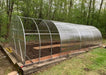 Partially assembled GreenhouseToGrow Camellia 10x32.5 Greenhouse Kit showing the transition from the steel frame to polycarbonate panel installation.