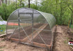 Front entrance of the GreenhouseToGrow Camellia 10x13 Greenhouse Kit highlighting the wide door and internal wood-framed raised garden beds.