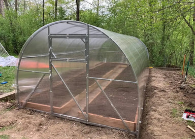 Front-facing exterior view of the GreenhouseToGrow Camellia 10x32.5 Greenhouse Kit with polycarbonate walls and soil-ready raised beds inside.