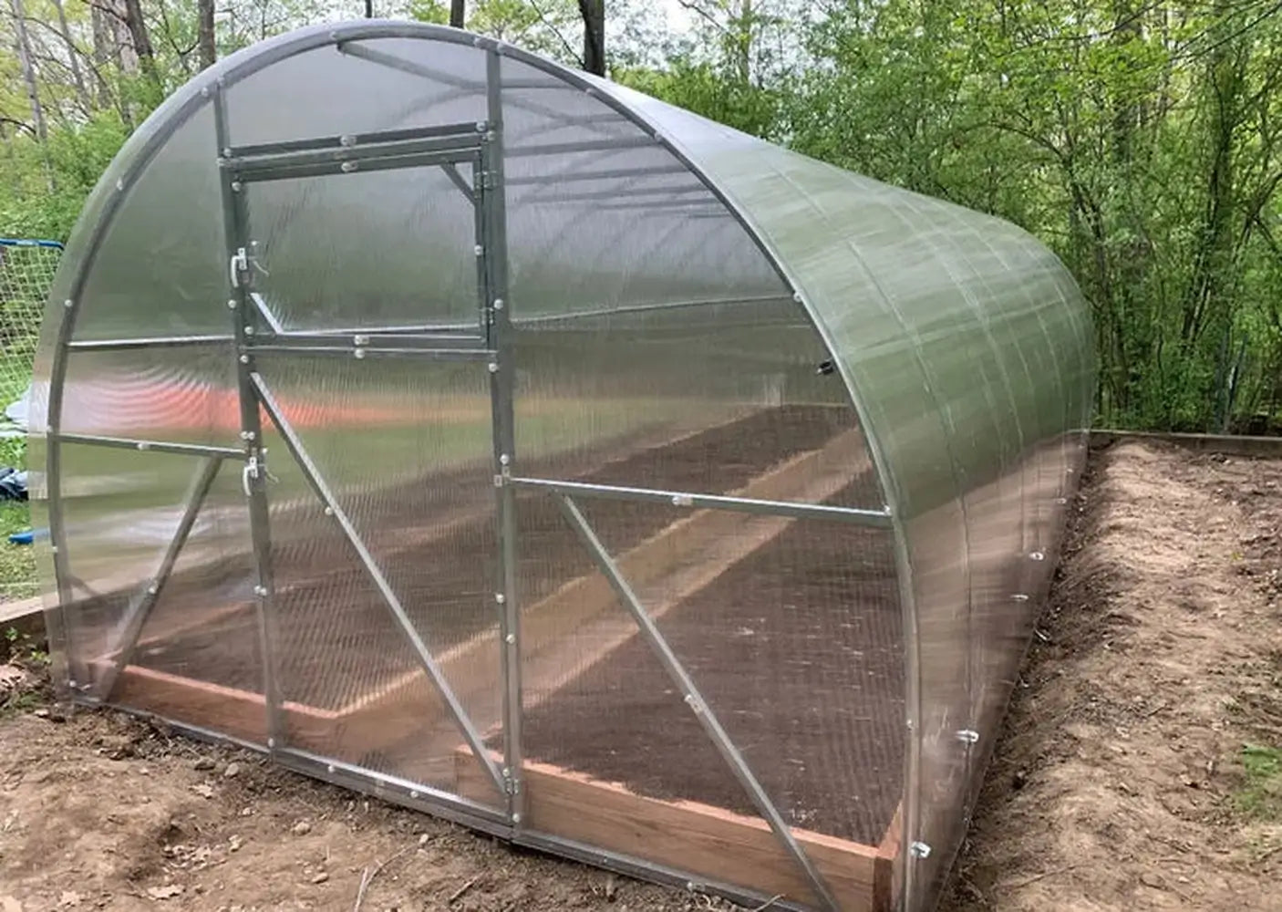 Wide-angle front view of the finished GreenhouseToGrow Camellia 10x32.5 Greenhouse Kit featuring a reinforced double-door entry system.