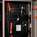 Close-up of AIMS Power LiFePO4 battery module ports, B terminals, COM connections, on/off switch, and orange power cables.