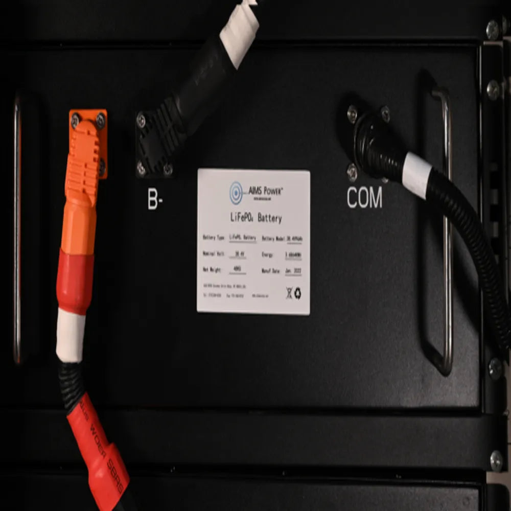 Close-up of AIMS Power lithium battery module label, COM port, B- terminal, orange connector, and black communication cable.