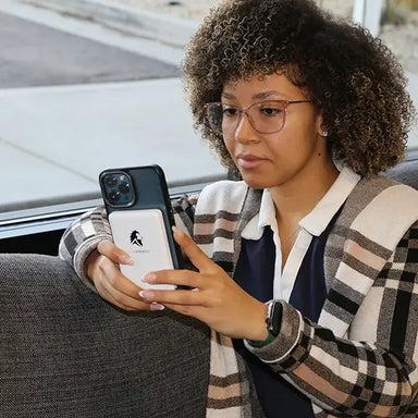 Woman using iPhone with Lion Energy Lion Claw MagSafe battery pack