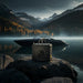 Single Lion Energy UT 1300 BT-H battery on a rock beside a sleek black boat on a misty mountain lake, showcasing rugged portable battery use in outdoor marine settings