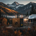Lion Energy UT 1300 BT-H 105Ah lithium iron phosphate battery on a rock at a mountain campsite beside a silver travel trailer, with snowy peaks and autumn trees in the background