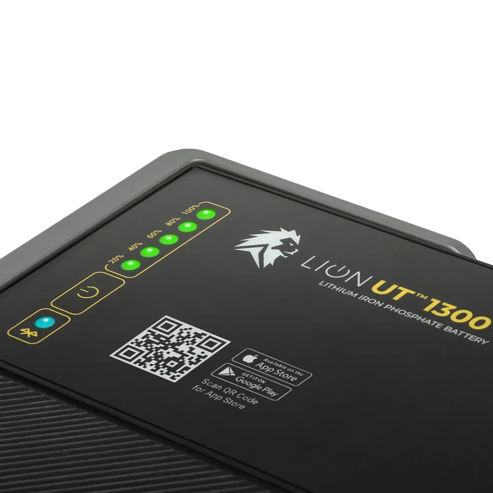 Close-up of the Lion Energy UT 1300 BT-H battery top panel showing green charge indicator lights, Bluetooth icon, QR code, and app store badges