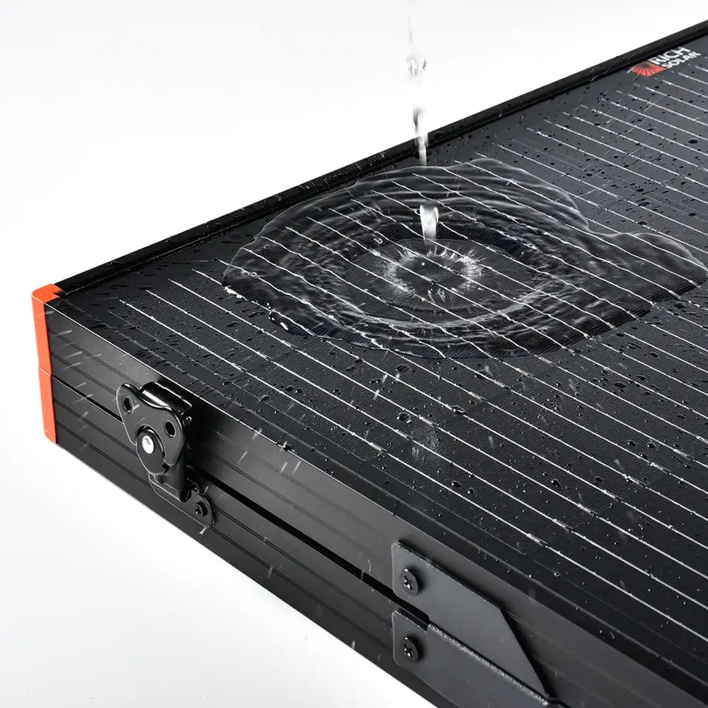Water droplets splashing onto the weatherproof monocrystalline glass surface of a Rich Solar MEGA 200W solar panel to demonstrate water resistance.