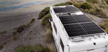 Off-grid camper van RV roof installation featuring multiple Rich Solar MEGA 250W solar panels parked near a coastal overlook.