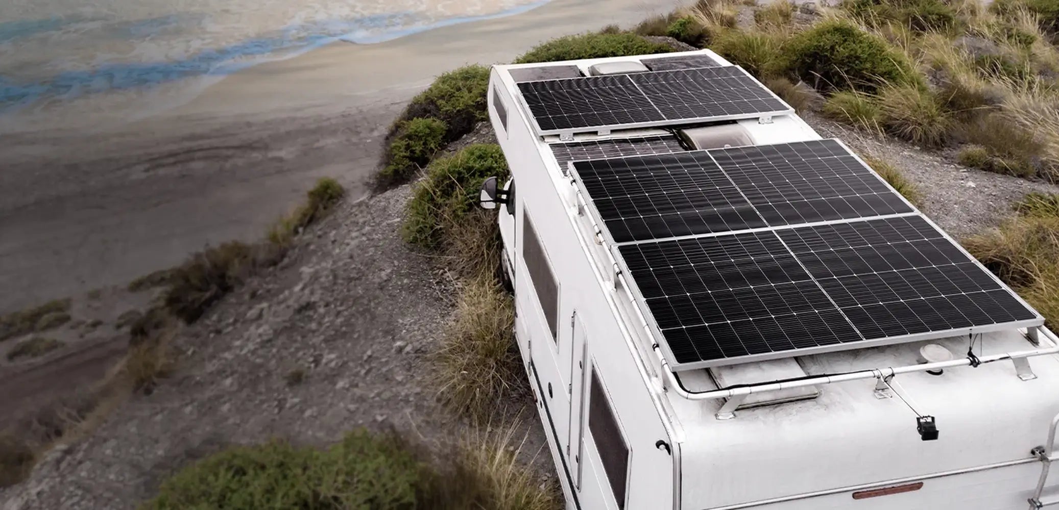 Off-grid camper van RV roof installation featuring multiple Rich Solar MEGA 250W solar panels parked near a coastal overlook.