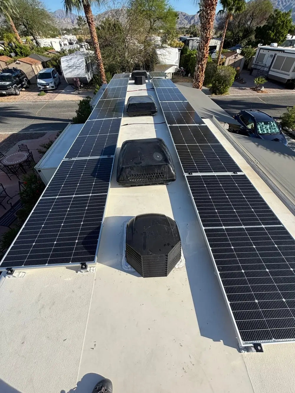 Full off-grid RV roof solar installation featuring two rows of Rich Solar MEGA 250 PRO 24V solar panels on a motorhome parked outdoors.