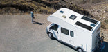 Two Rich Solar MEGA 130W Slim Solar Panels mounted flat on the roof of a white motorhome RV parked in a desert landscape.