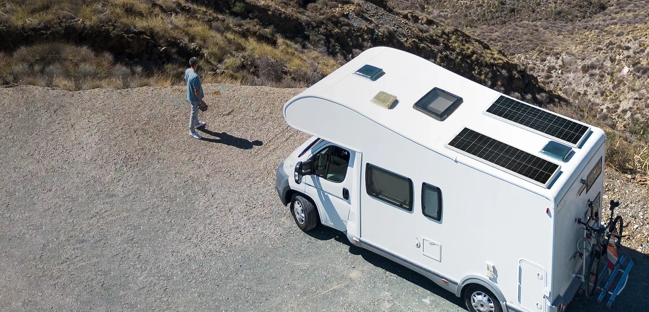 Two Rich Solar MEGA 130W Slim Solar Panels mounted flat on the roof of a white motorhome RV parked in a desert landscape.