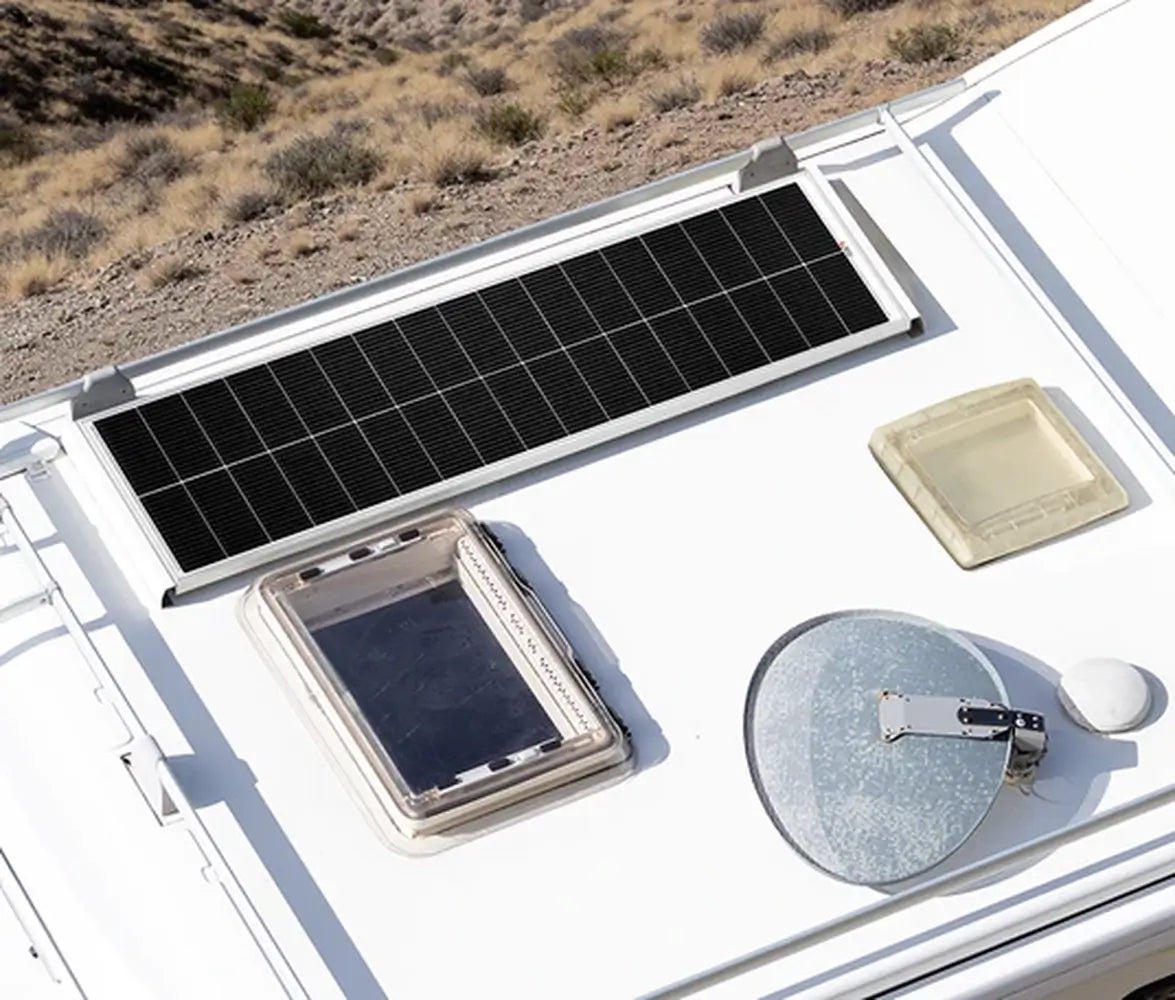 Close-up overhead view of a Rich Solar MEGA 130W Slim Solar Panel mounted on a white camper roof next to skylights and an antenna.