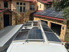 High-density off-grid solar array featuring multiple Rich Solar 250W panels mounted across a custom RV roof parked next to a residential home.