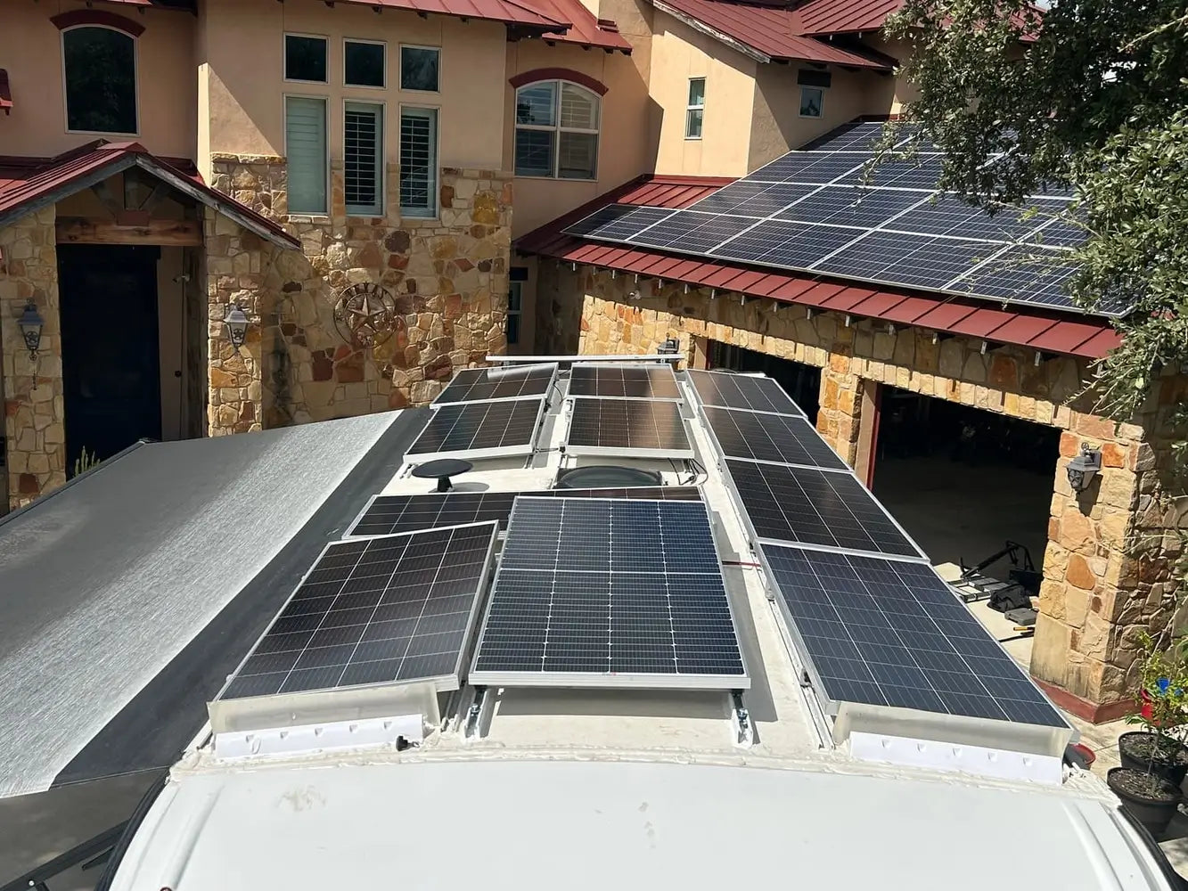 High-density off-grid solar array featuring multiple Rich Solar 250W panels mounted across a custom RV roof parked next to a residential home.