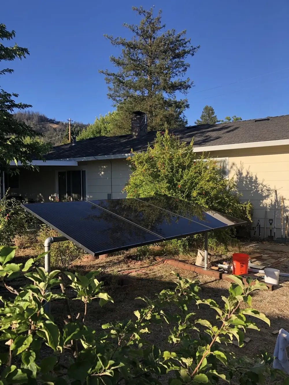 Ground-mounted solar array featuring three Rich Solar 335W all-black solar panels in a residential backyard setup.