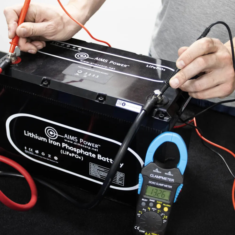 AIMS Power 600V True RMS clamp meter testing lithium iron phosphate battery voltage and terminals.